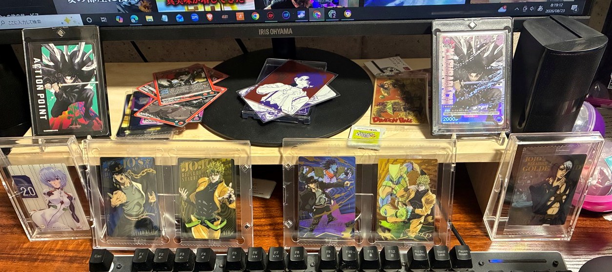 100均の透明ケースに入れたアニメのカードやシールをパソコンデスクに飾っている様子